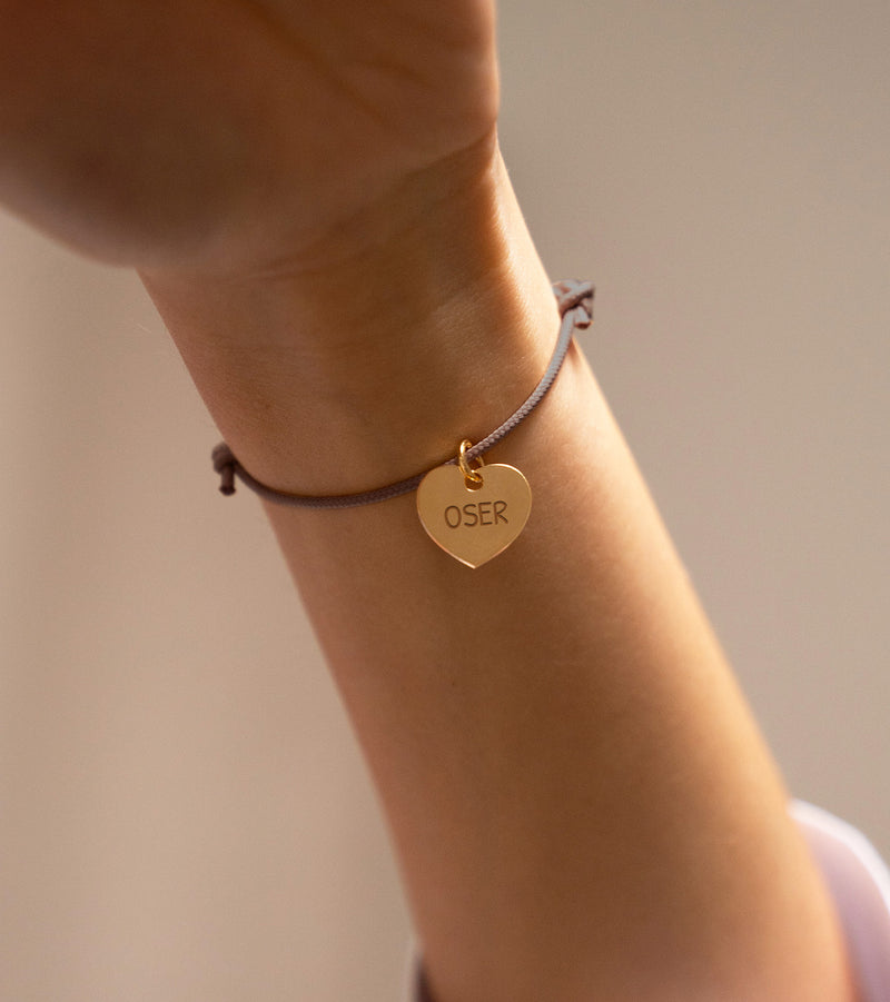 Un bracelet, orné d'un cœur plaqué or de 15mm, assorti d'un cordon en nuances de marron clair.