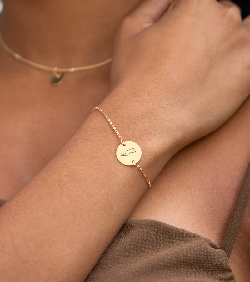 Bracelet en plaqué or, agrémenté d'une médaille personnalisée de 15mm, offre une touche de raffinement avec sa chaîne plate et ses deux trous distinctifs.