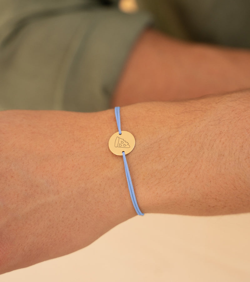 Ce bracelet, orné d'une médaille de 15mm et de deux trous, est plaqué or avec un cordon bleu pastel.