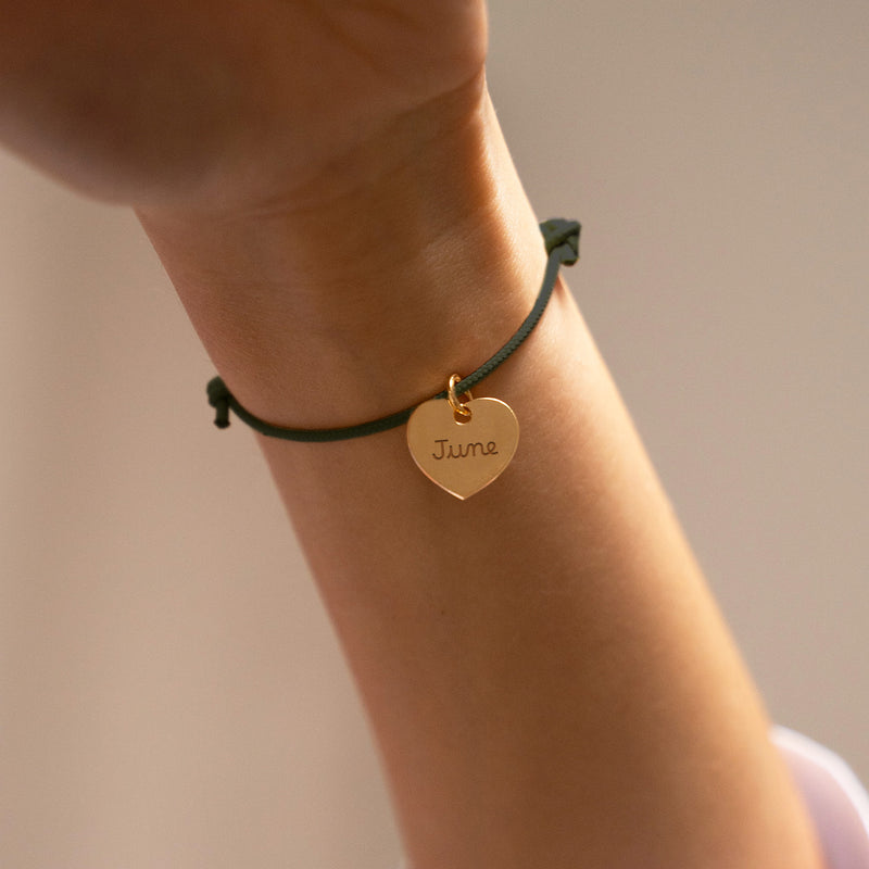 Un bracelet plaqué or, orné d'un cœur de 15mm, personnalisé sur un cordon kaki.