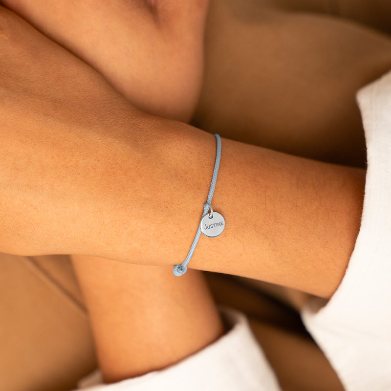 Un bracelet unique. Une médaille en argent de 10mm sur un cordon bleu pastel, personnalisé selon vos désirs.