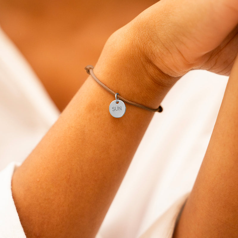 Bracelet argenté avec médaille 10mm personnalisée, sur cordon marron clair, ajoutant une note personnelle à votre look.