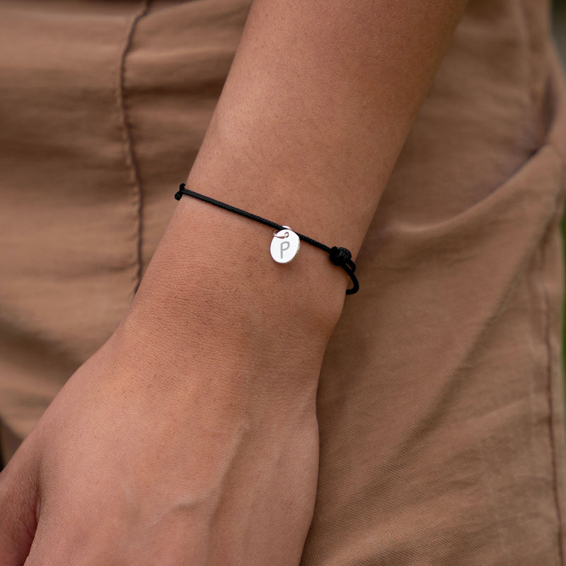 Accessoire chic, bracelet personnalisé orné d'une médaille argentée de 10mm sur cordon noir.