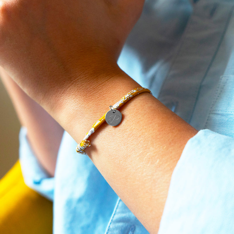 Médaille argentée de 10mm sur un bracelet personnalisé avec un lien liberty Clivia, un accessoire raffiné et moderne.