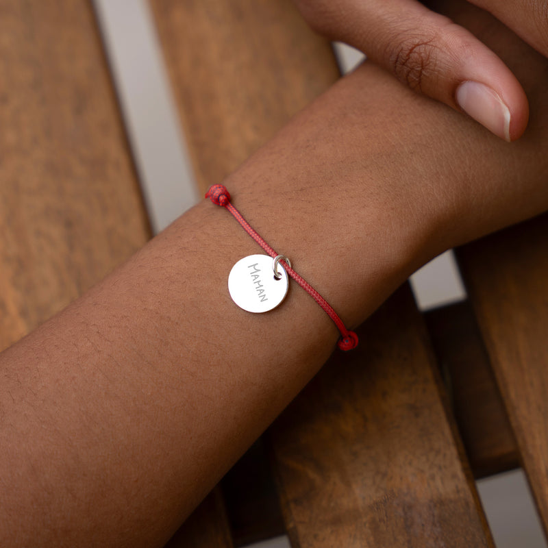 Bracelet personnalisé en argent orné d'une médaille de 15mm, agrémenté d'un cordon rouge distinctif.