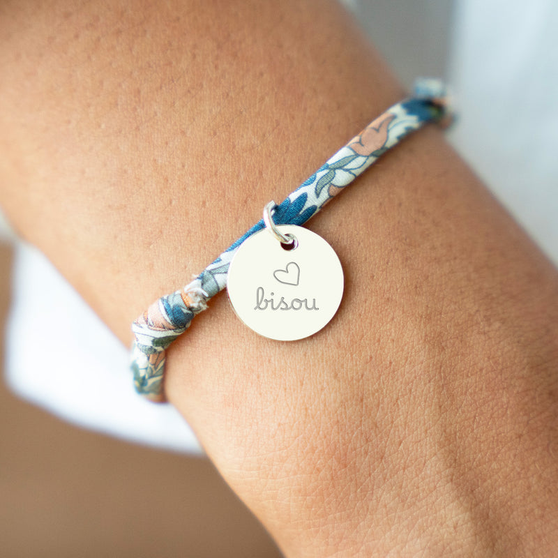 Un bracelet argenté avec une médaille de 15mm sur un lien Liberty lilas.
