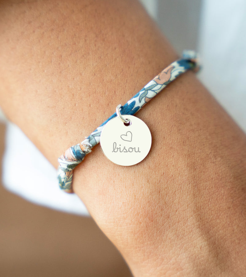 Un bracelet argenté avec une médaille de 15mm sur un lien Liberty lilas.