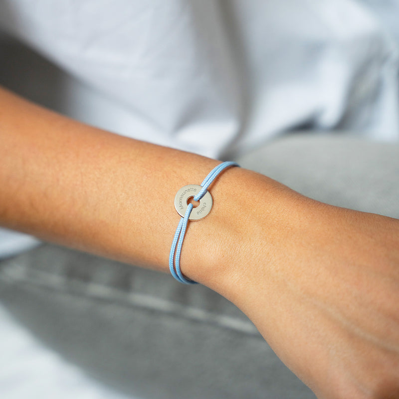 Avec un cordon bleu pastel, ce bracelet en forme de cible est personnalisé de 15mm en argent.