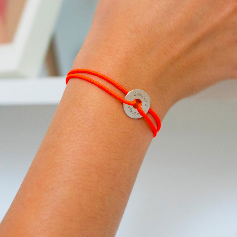 Un bracelet en forme de cible, personnalisé de 15mm en argent, avec un cordon orange fluo.