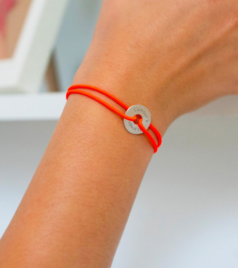 Un bracelet en forme de cible, personnalisé de 15mm en argent, avec un cordon orange fluo.