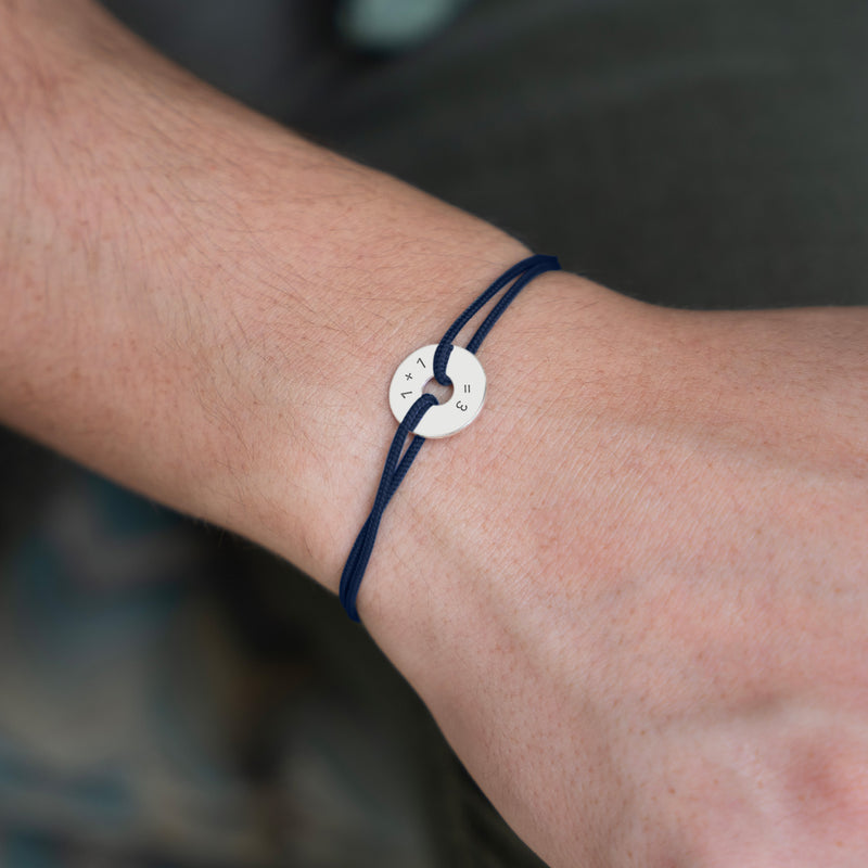 Ce bracelet, conçu en forme de cible, présente une personnalisation de 15mm en argent et un cordon bleu marine.