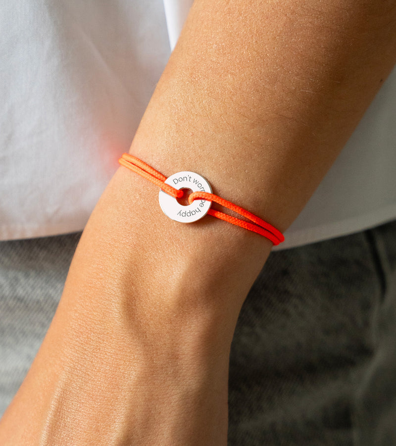Personnalisé de 15mm en argent, ce bracelet en forme de cible est rehaussé d'un cordon orange fluo.