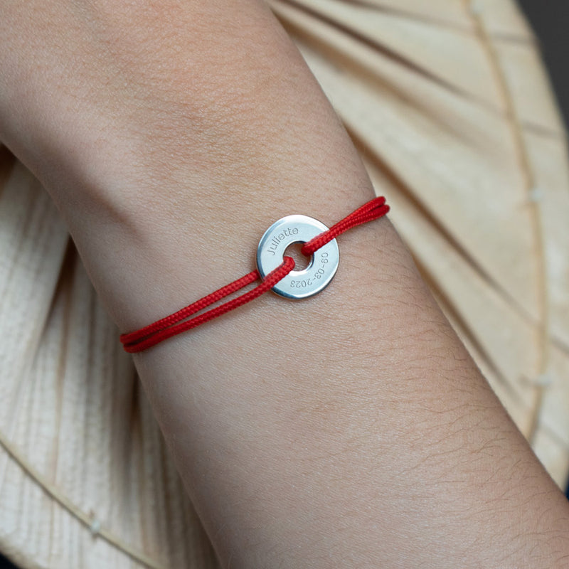 Personnalisé de 15mm en argent, ce bracelet en forme de cible est rehaussé d'un cordon rouge.