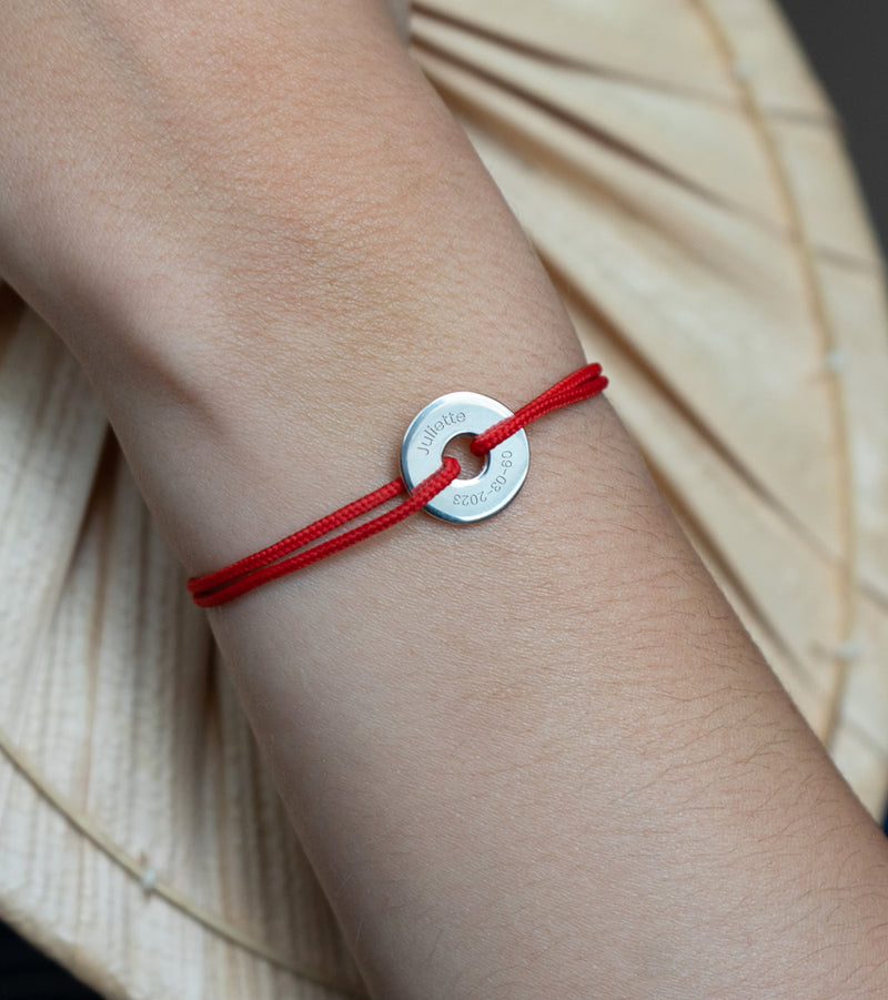 Personnalisé de 15mm en argent, ce bracelet en forme de cible est rehaussé d'un cordon rouge.