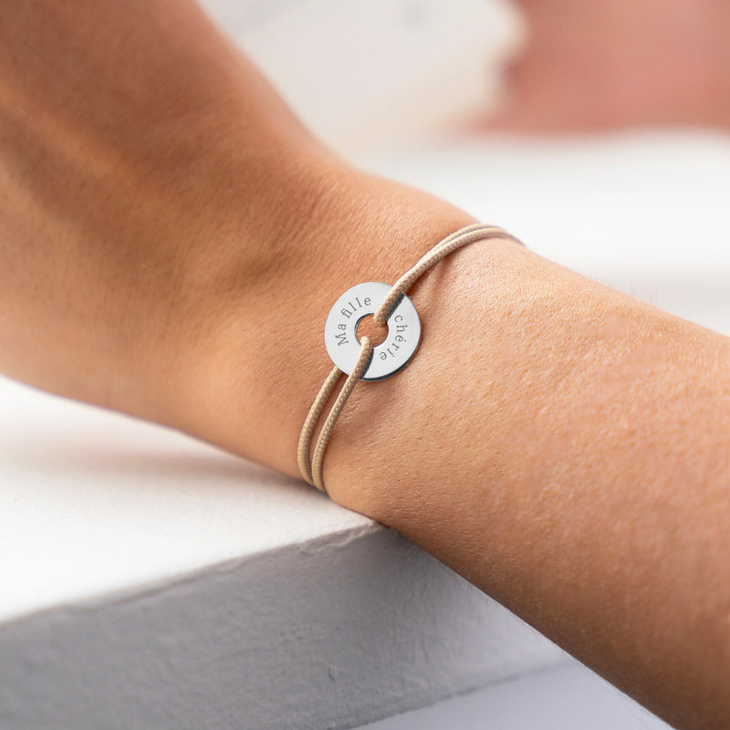 "Personnalisé de 15mm en argent, ce bracelet en forme de cible est rehaussé d'un cordon beige. "