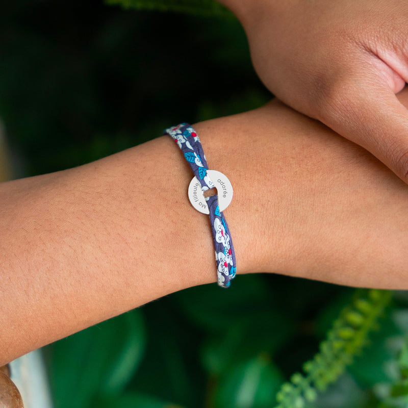 Le bracelet en forme de cible, embelli d'une médaille de 15mm en argent personnalisé, est sublimé par un lien en Liberty Iris.