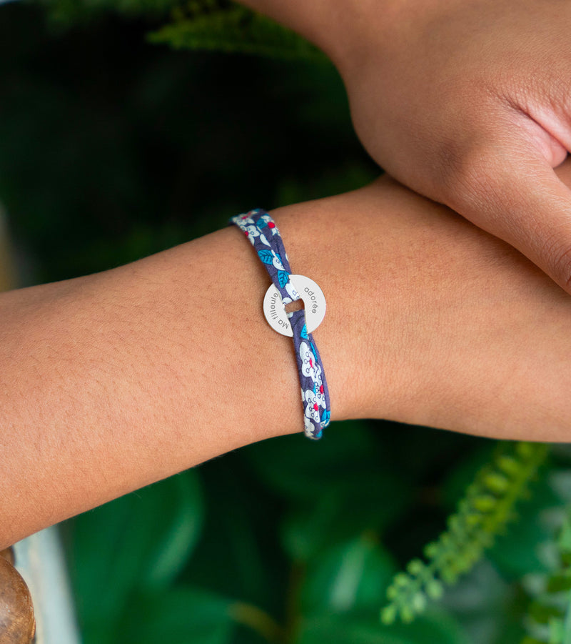Le bracelet en forme de cible, embelli d'une médaille de 15mm en argent personnalisé, est sublimé par un lien en Liberty Iris.