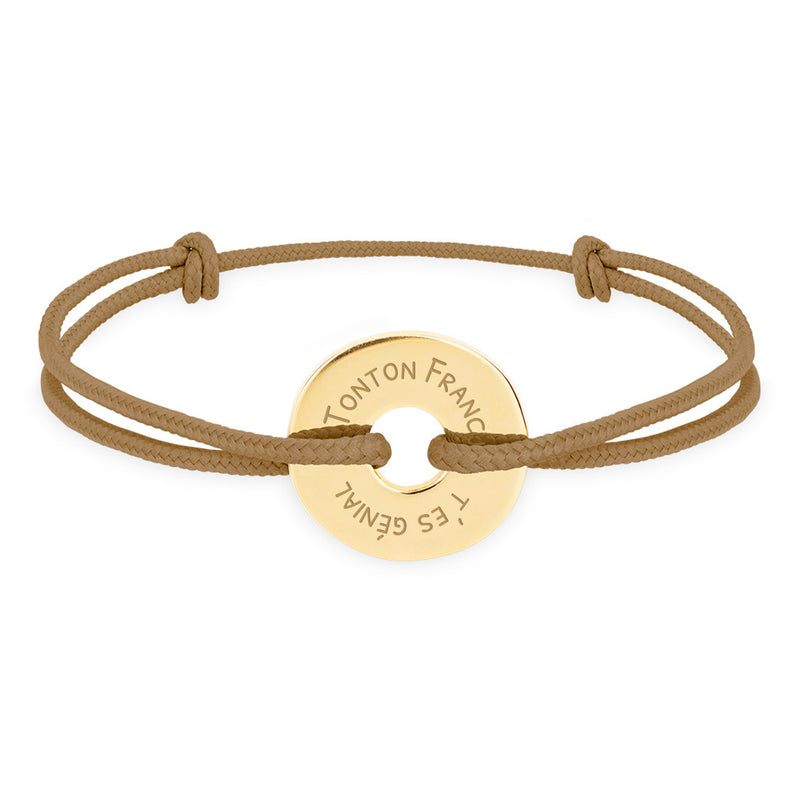 Ce bracelet plaqué or, en forme cible de 15mm, personnalisé selon vos envies, est complété par un cordon marron clair.