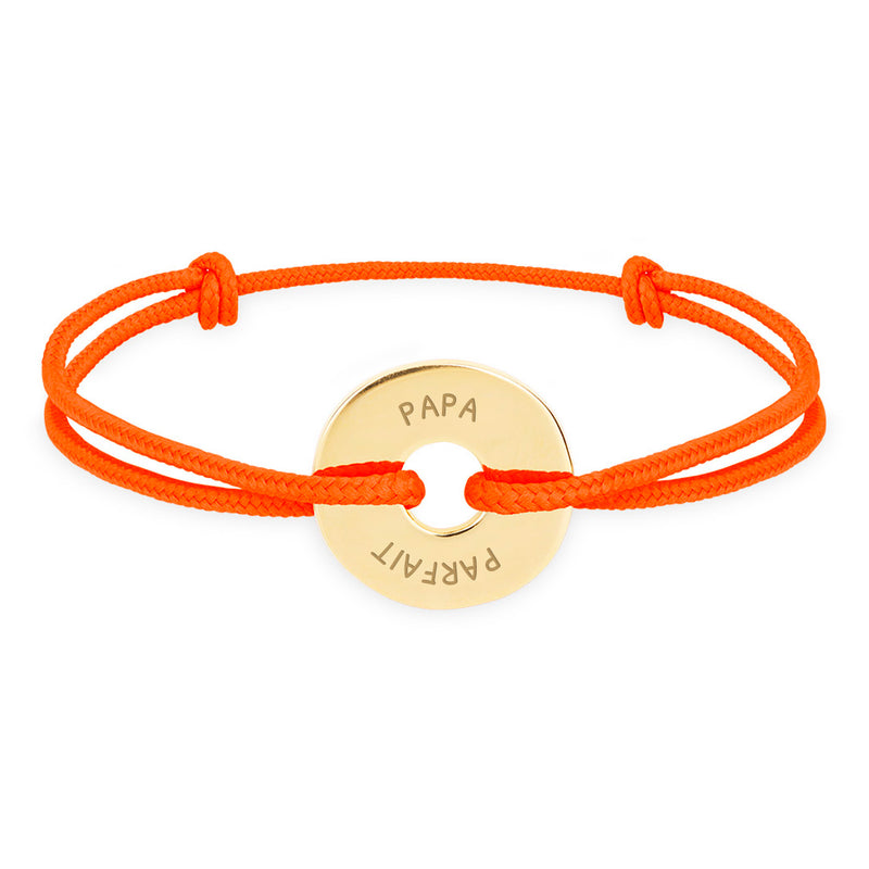 Un bracelet plaqué or, personnalisé en 15mm et agrémenté d'un cordon orange fluo, avec sa forme de cible.