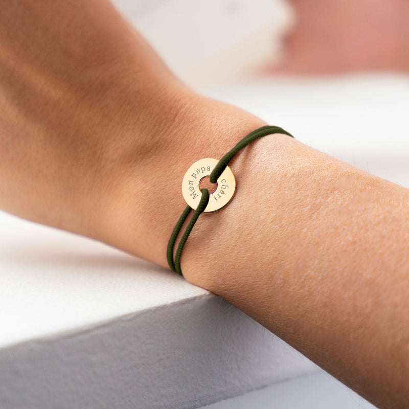 Avec une forme cible, ce bracelet personnalisé en 15mm, plaqué or, est agrémenté d'un cordon bleu kaki.