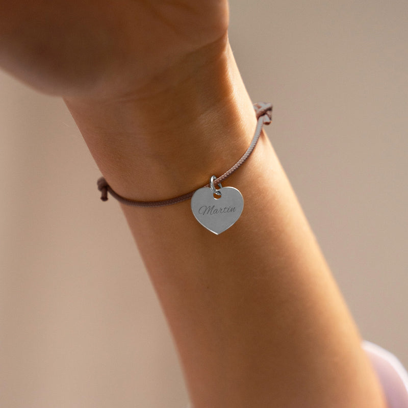 Une représentation visuelle d'un bracelet coeur argenté, de 15mm, avec un cordon en marron clair, personnalisable.