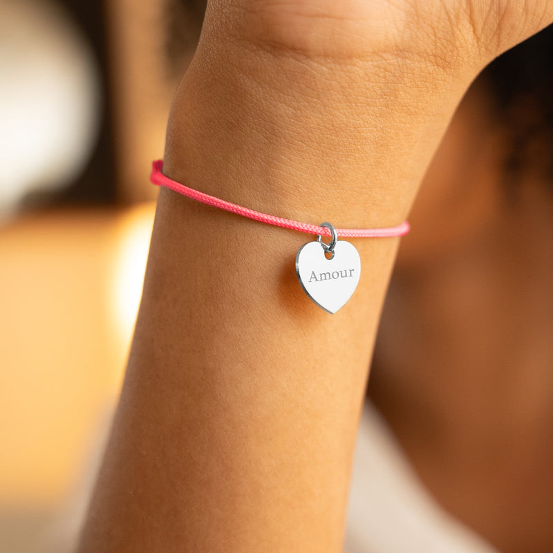 Regardez ce bracelet argenté, un cœur brillant sur un cordon rose fuchsia.
