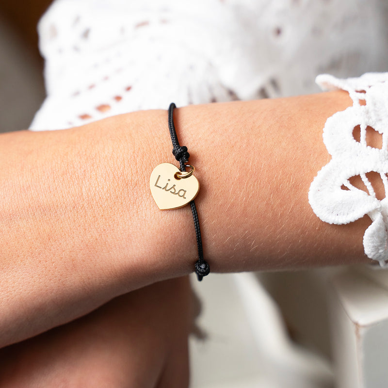 Bracelet cœur doré de 15 mm sur un cordon noir.