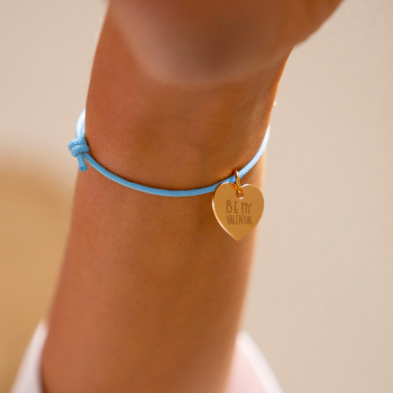Un bijou unique : un bracelet charmant avec un cœur doré de 15mm, suspendu avec grâce sur un cordon bleu pastel, capturant l'essence de l'amour et de la personnalisation.