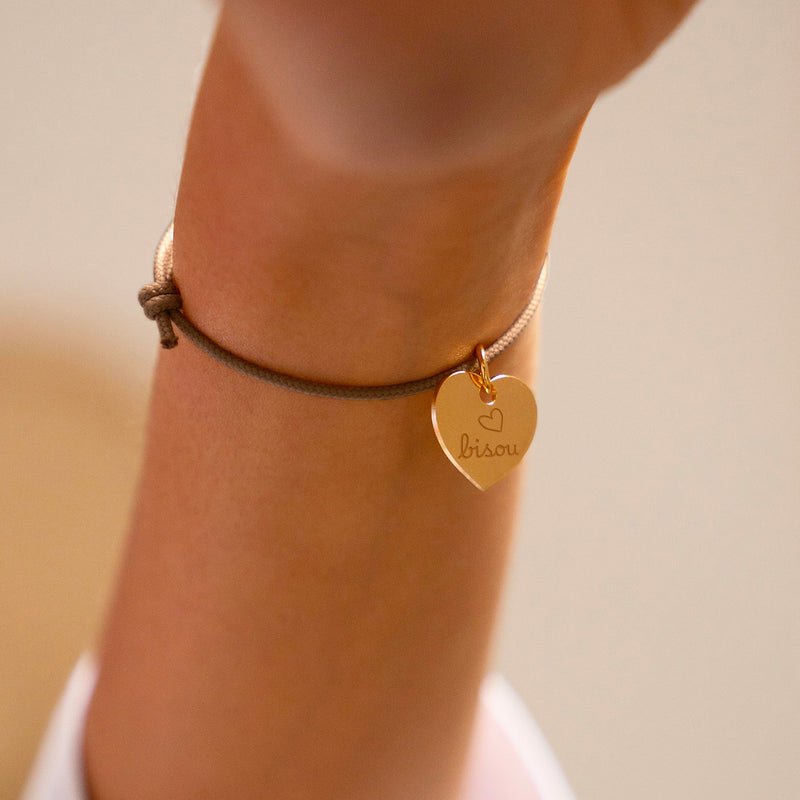 Un bracelet, arborant un cœur plaqué or de 15mm, assorti d'un cordon marron clair.