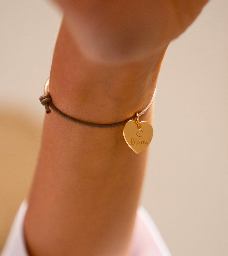 Un bracelet, arborant un cœur plaqué or de 15mm, assorti d'un cordon marron clair.