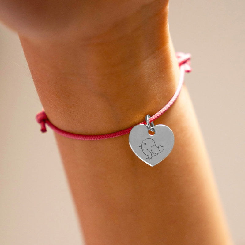 Découvrez ce bracelet argenté avec un cœur et un cordon rose fuchsia.