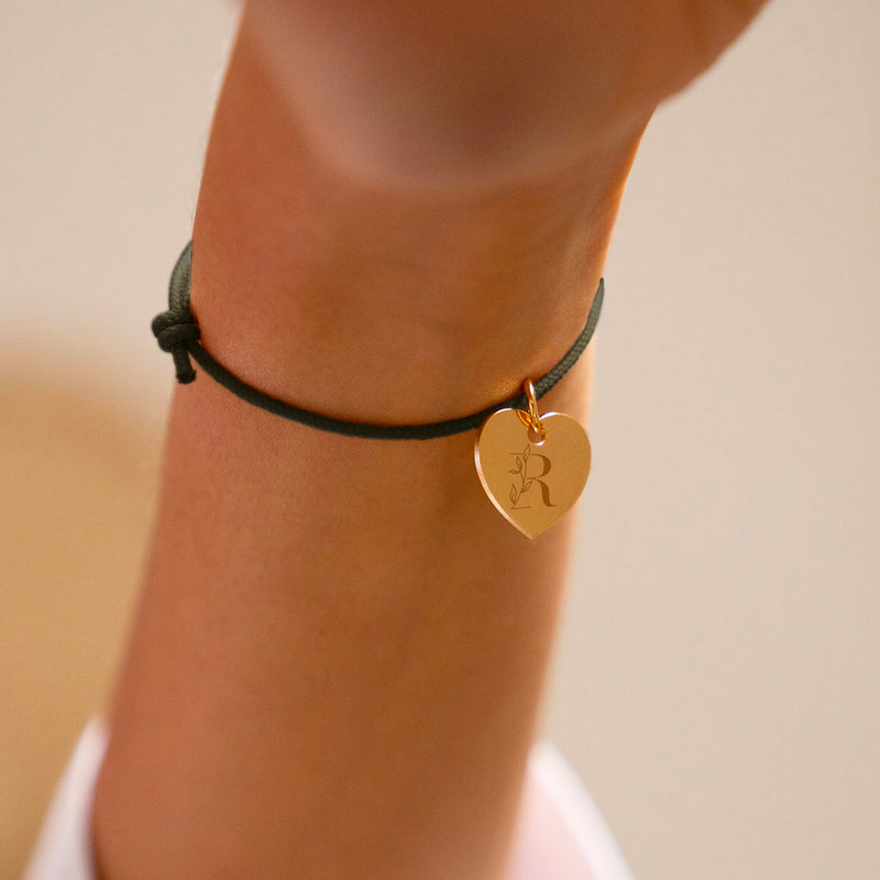 Un bracelet personnalisé avec un cœur de 15mm en plaqué or, attaché à un cordon kaki.