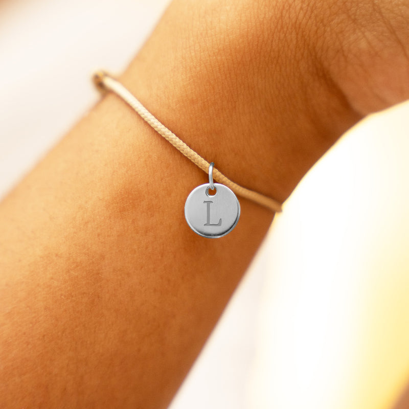 Bracelet en argent orné d'une médaille de 10mm sur cordon beige.