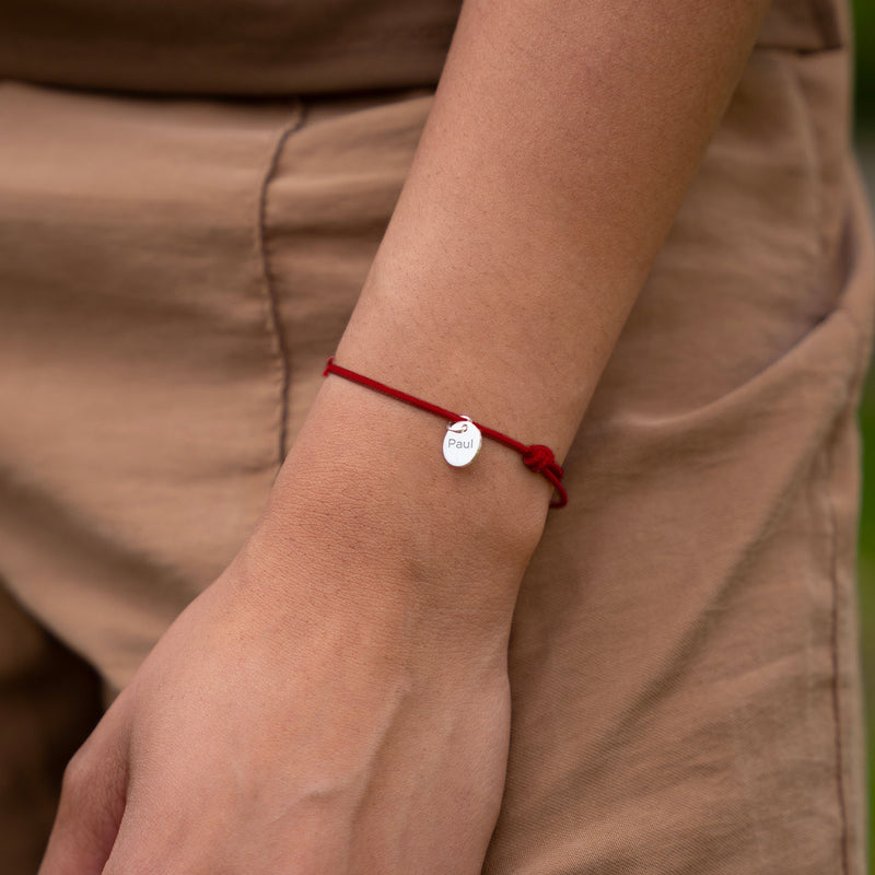 Un bracelet argenté avec une médaille de 10mm et un cordon rouge personnalisable.