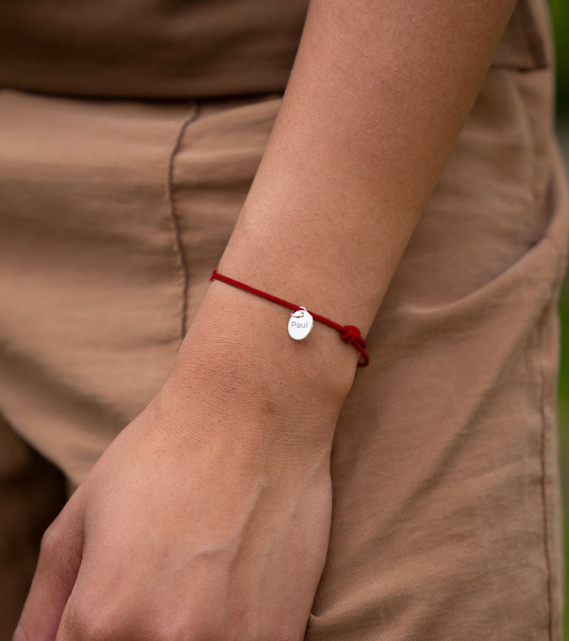 Un bracelet argenté avec une médaille de 10mm et un cordon rouge personnalisable.