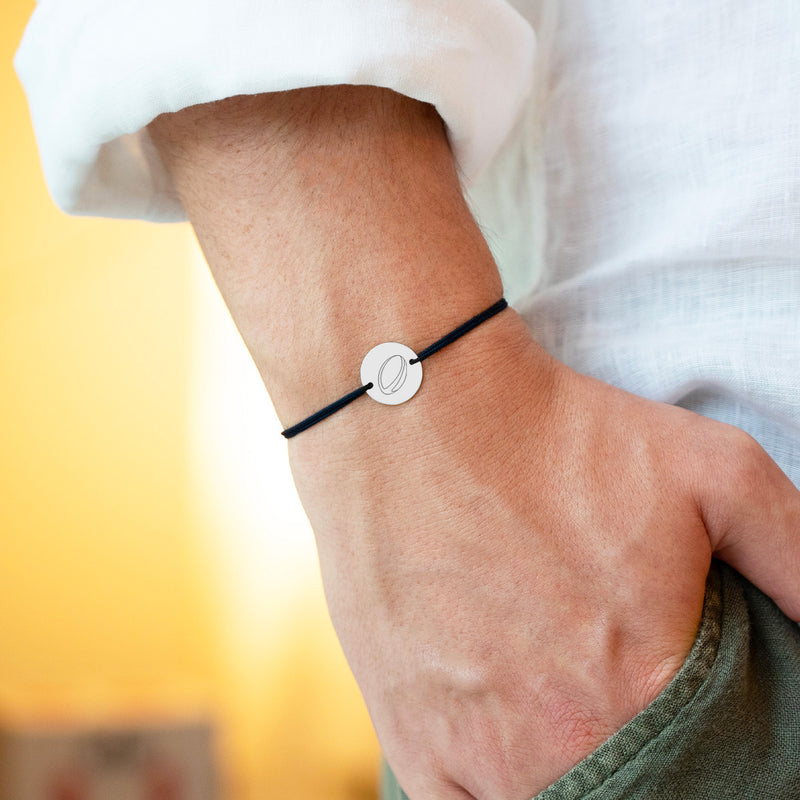 un bracelet en argent de 15mm avec une médaille personnalisée, attachée à un cordon noir doté de deux trous.