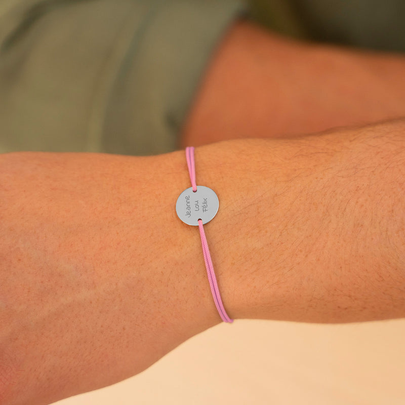 Un bracelet argenté éclatant, mis en valeur par une médaille de 15mm personnalisée avec 2 trous, accompagné d'un cordon rose raffiné.