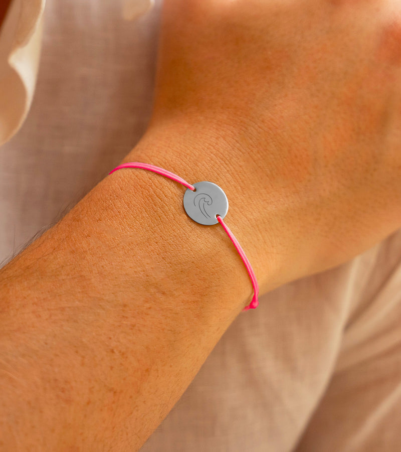 Un bracelet personnalisé orné d'une médaille argentée de 15mm et doté de 2 trous, rehaussé d'un cordon rose fuchsia
