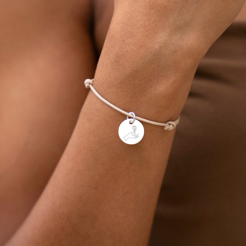 Un bracelet avec médaille de 15mm, personnalisable, sur un cordon beige.