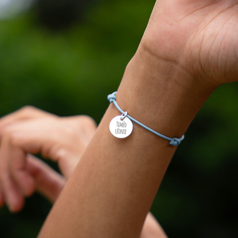 Bracelet argenté personnalisé, médaille 15mm sur cordon bleu pastel. Parfait pour compléter votre tenue avec une touche de personnalisation.