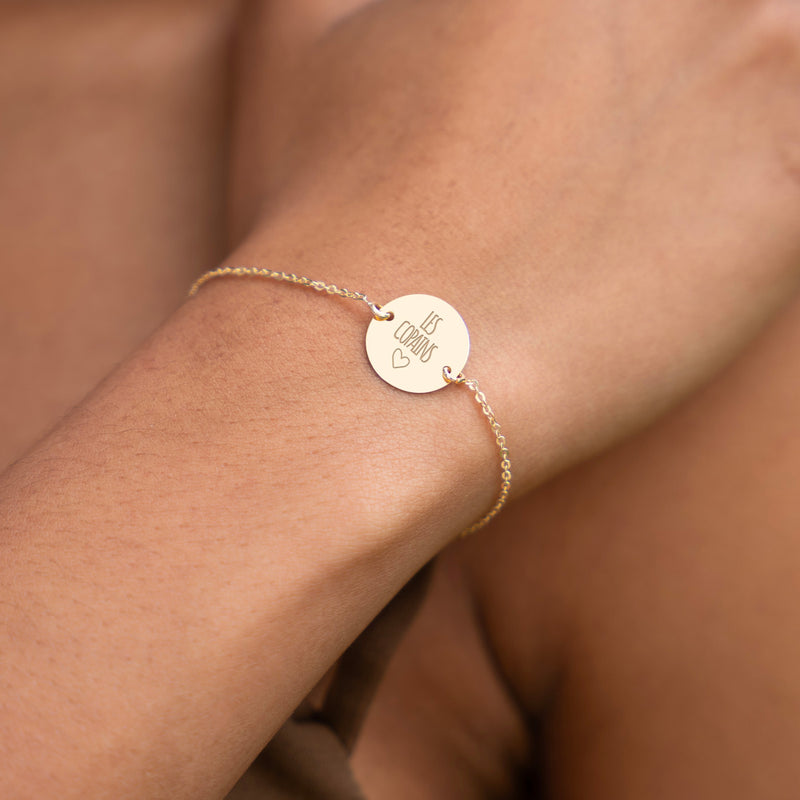 Un bracelet finement plaqué or, orné d'une médaille personnalisée de 15mm, présente deux trous et une chaîne plate.