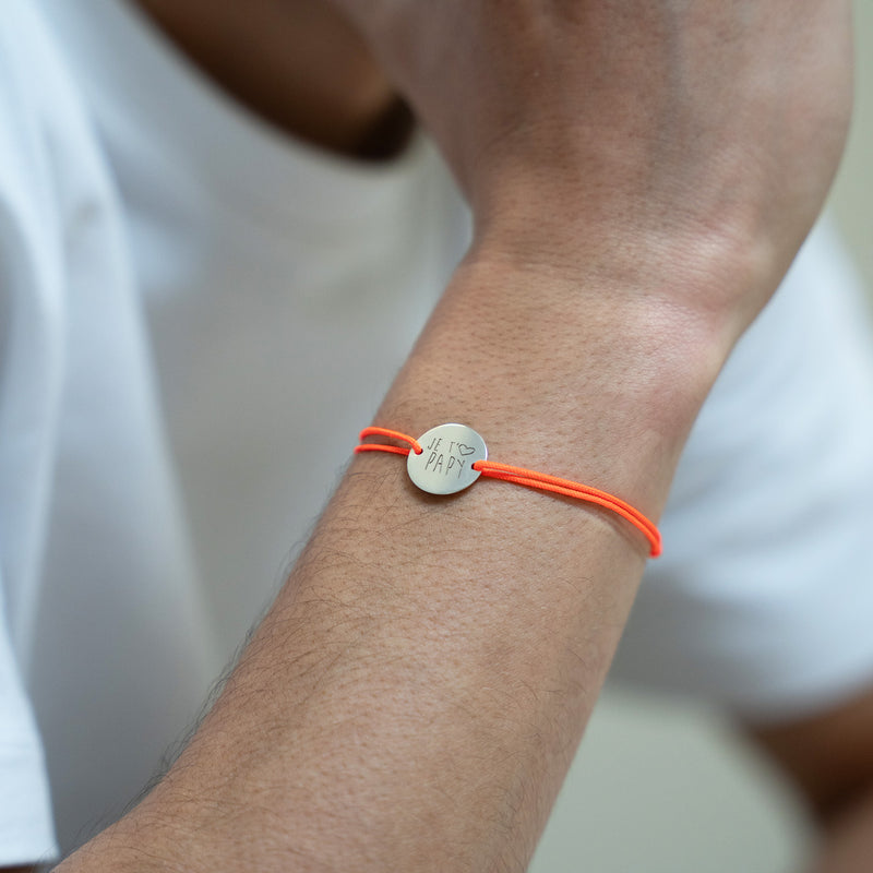 "Une médaille de 15mm personnalisée, encerclée par un cordon orange fluo, sur un bracelet argenté à deux trous. "