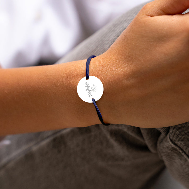 Le bracelet, avec sa médaille personnalisée en 20mm, présente deux trous argent et un cordon bleu marine.