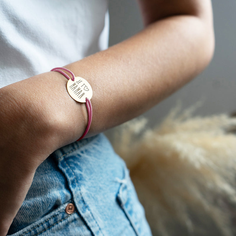 Un bracelet avec médaille sur mesure de 20mm, agrémenté de deux trous plaqués or et d'un cordon rose.