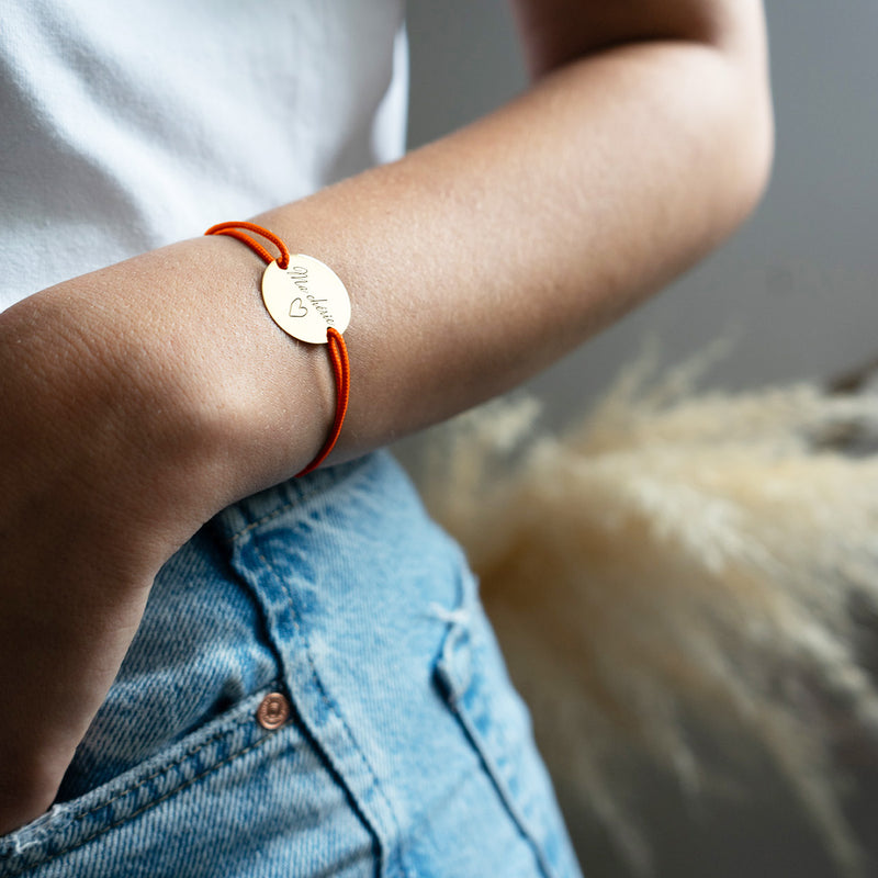 une médaille personnalisée en 20mm, ce bracelet possède deux trous en plaqué or et un cordon orange fluo