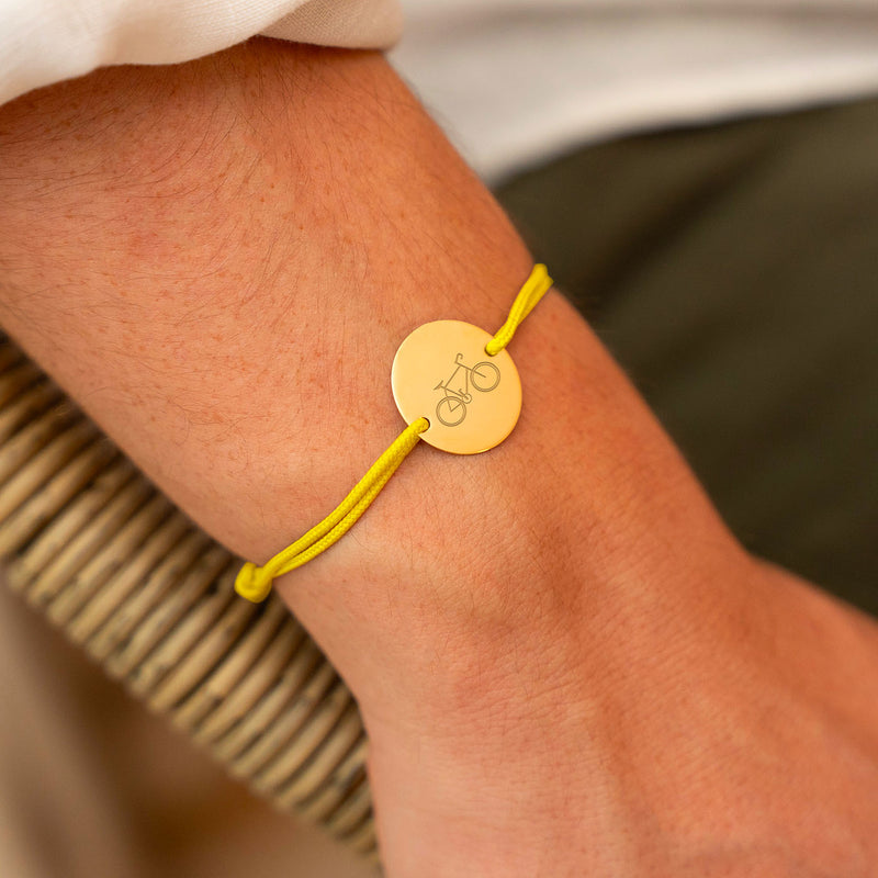 Un bijou qui roule avec vous ! Ce bracelet en médaille plaqué or et cordon jaune est fait pour les amoureux du vélo. Faites graver votre message et affichez votre style tout en pédalant !