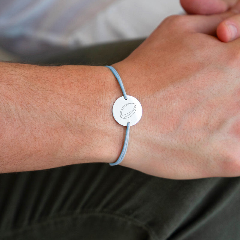 Une délicate médaille personnalisée de 15mm, montée sur un bracelet argenté à deux trous, contraste avec élégance le cordon bleu pastel