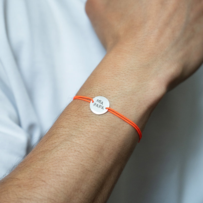Un bracelet argenté de 15mm, avec deux trous distinctifs pour un cordon orange fluo.