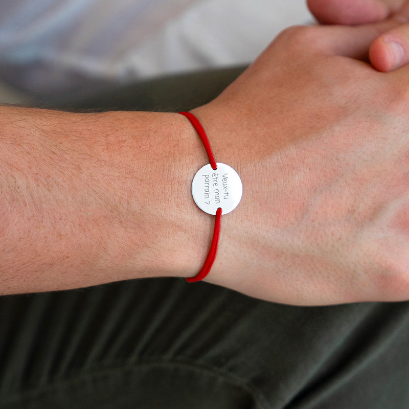 Médaille personnalisée argentée de 15mm avec 2 trous, sur un bracelet cordon rouge, pour un look distinctif.