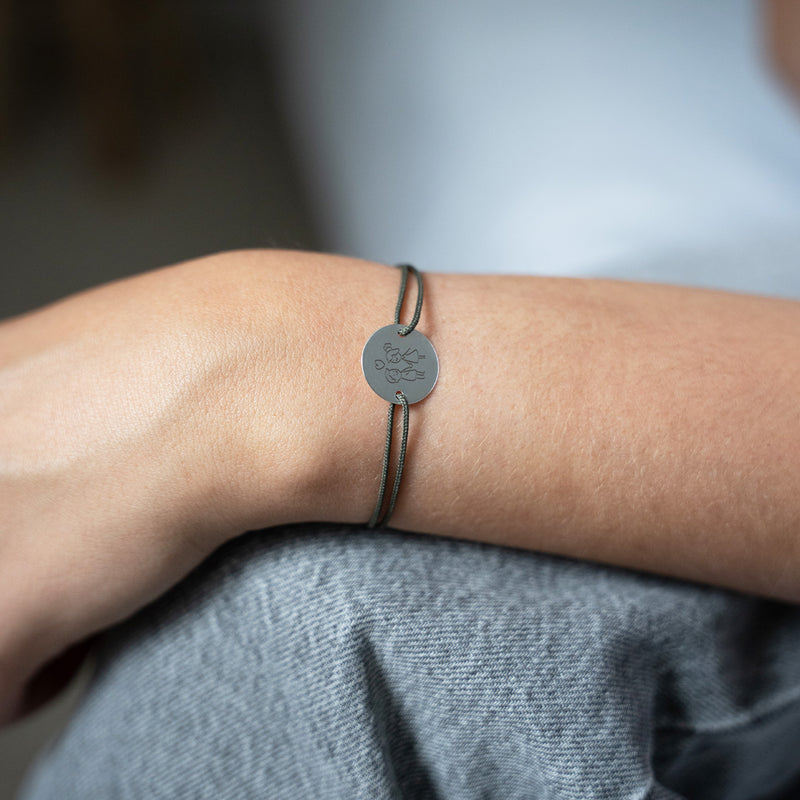 Élégant bracelet argenté avec une médaille personnalisée de 15mm, orné de deux trous distinctifs. Le cordon kaki ajoute une touche de sophistication à ce bijou unique.